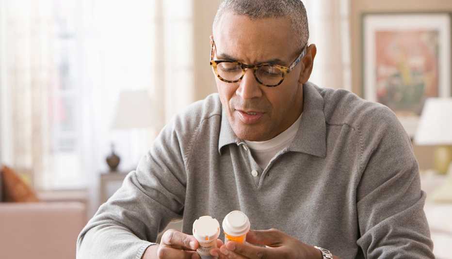 African American Man examining prescription bottles.