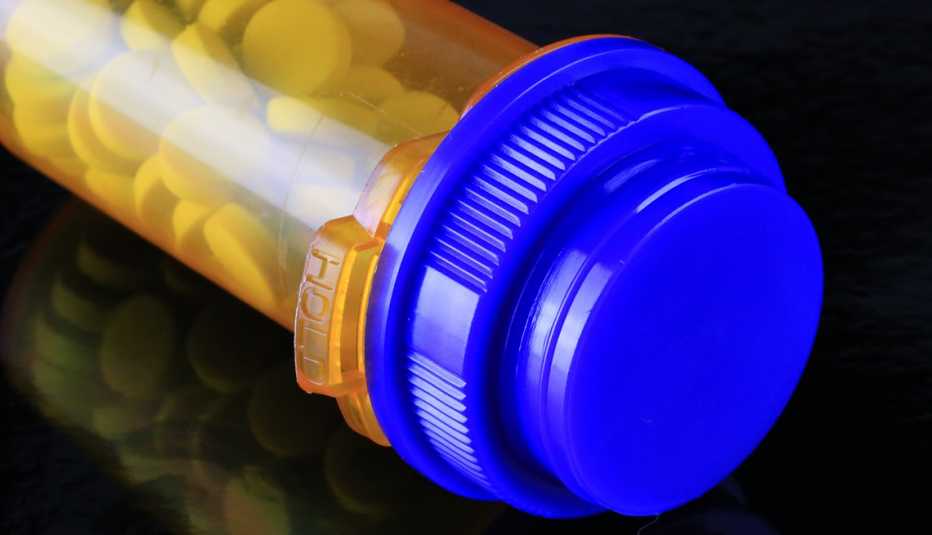 a prescription pill bottle laying on its side on a black backround
