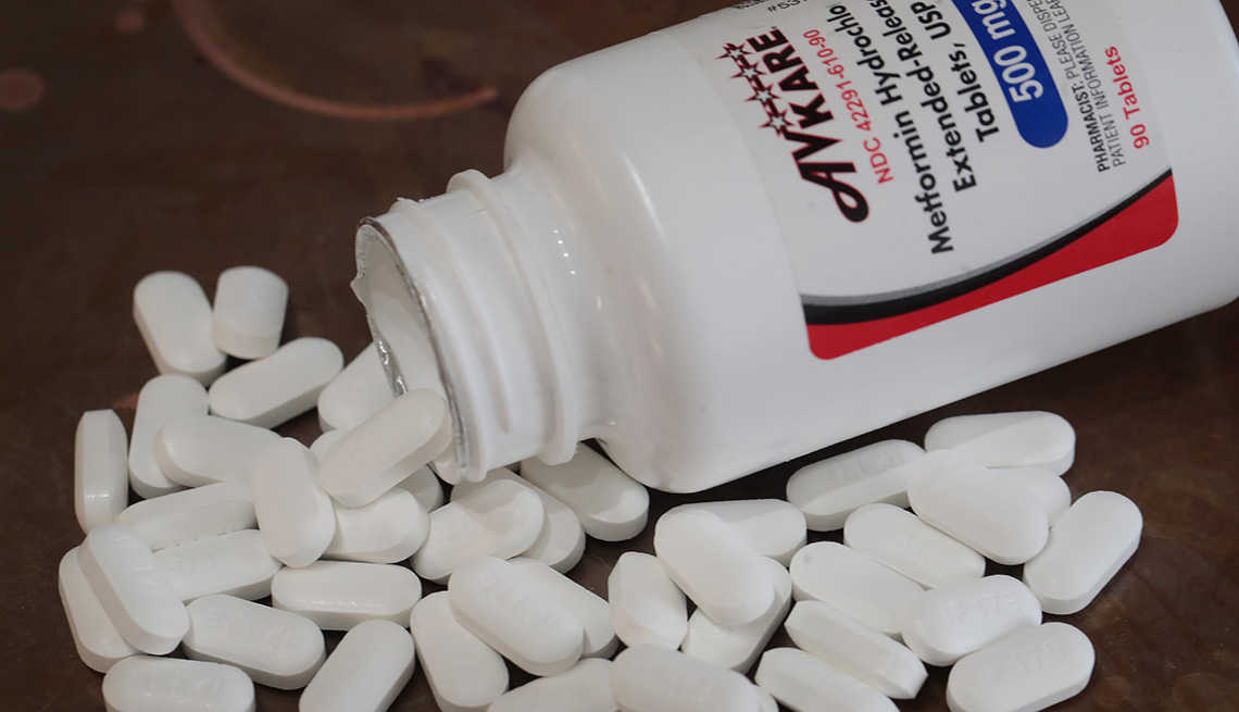 extended release metformin pills spilling out of their bottle on a table.