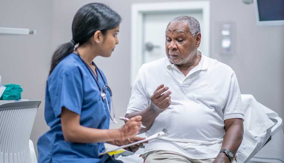 A man sitting on a bed in a doctor's office talking to a female doctor about participating in a clinical trial