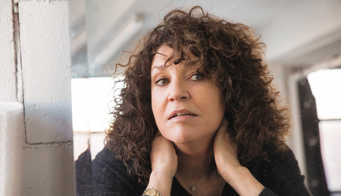woman with curly hair looking in the mirror, she looks concerned