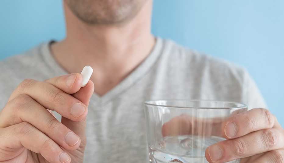 Man taking white pill of statin medicine
