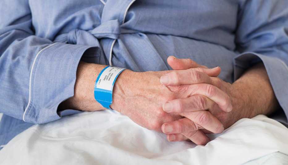 Mature man sitting in hospital bed, wearing a hospital wrist band.
