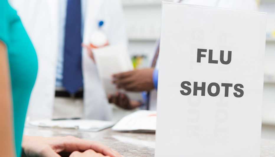 Woman standing at a pharmacy counter near a flu shot sign. 