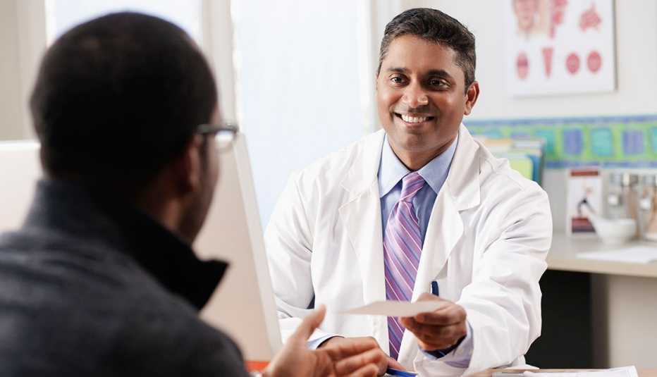 smiling doctor hands patient a prescription