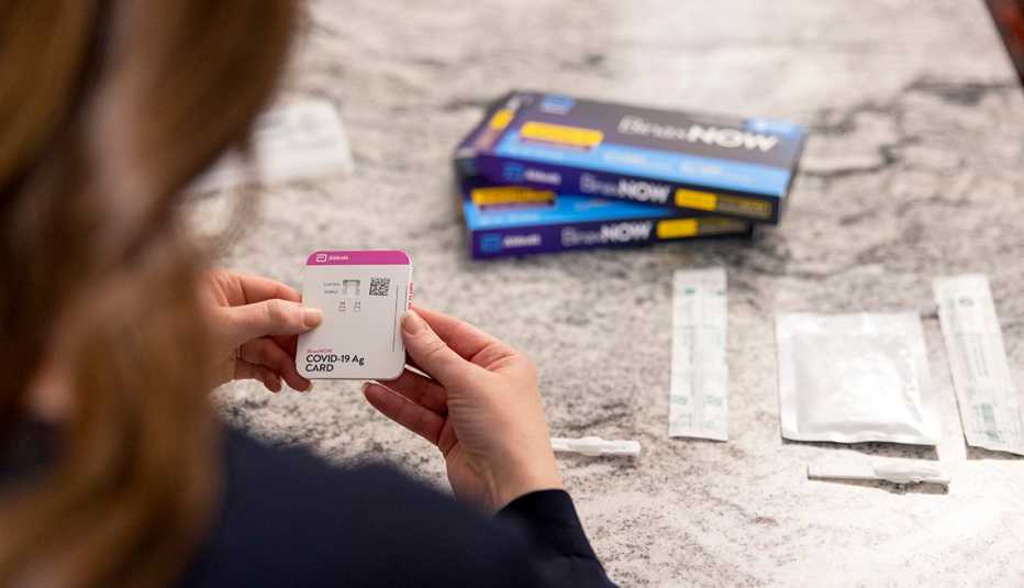 a woman reads the directions for the abbott binax rapid covid test