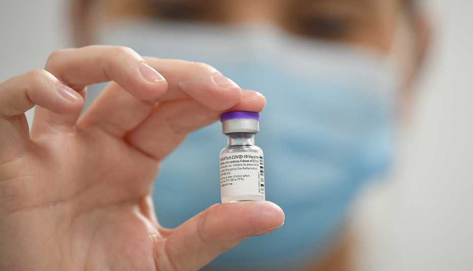 a health care holds a vial of COVID-19 vaccine
