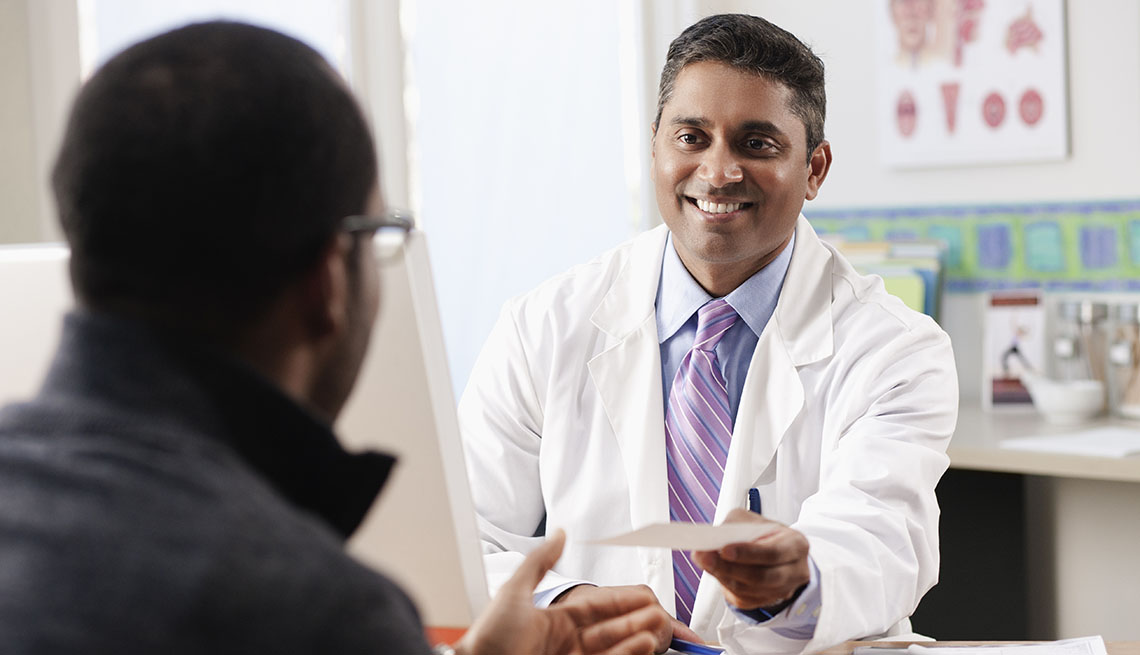 smiling doctor hands patient a prescription