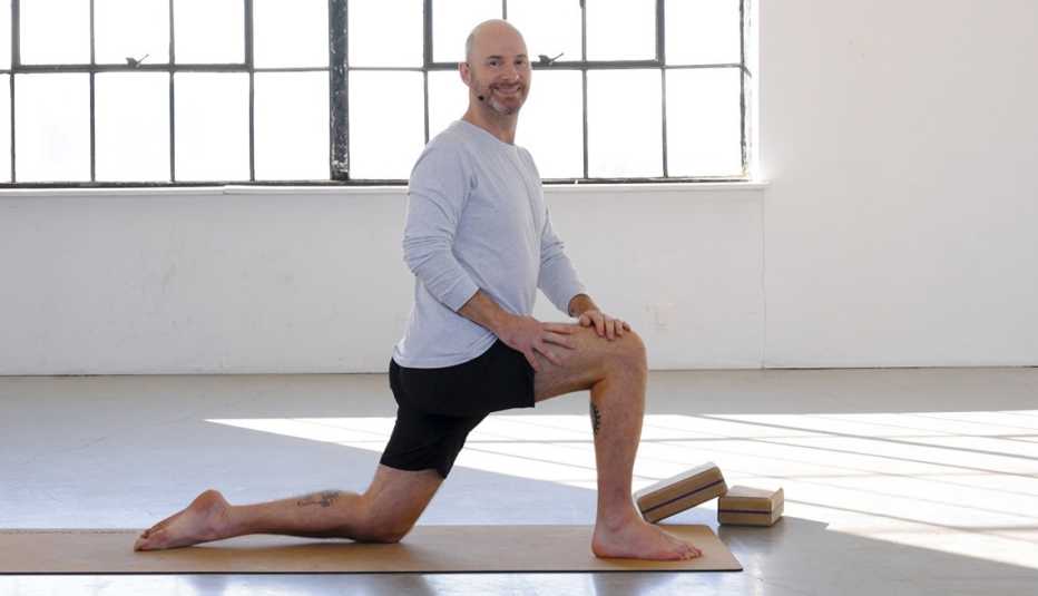 Side view of Bram Levinson with left knee on mat, right knee at 90 degrees with right foot on mat, hands on right knee