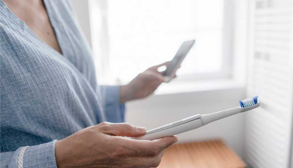 Close-up of woman with cell phone and toothbrush 