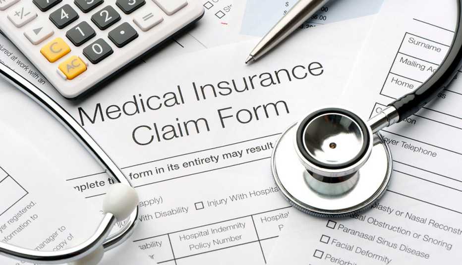Medical insurance forms next to a calculator, stethoscope and pen