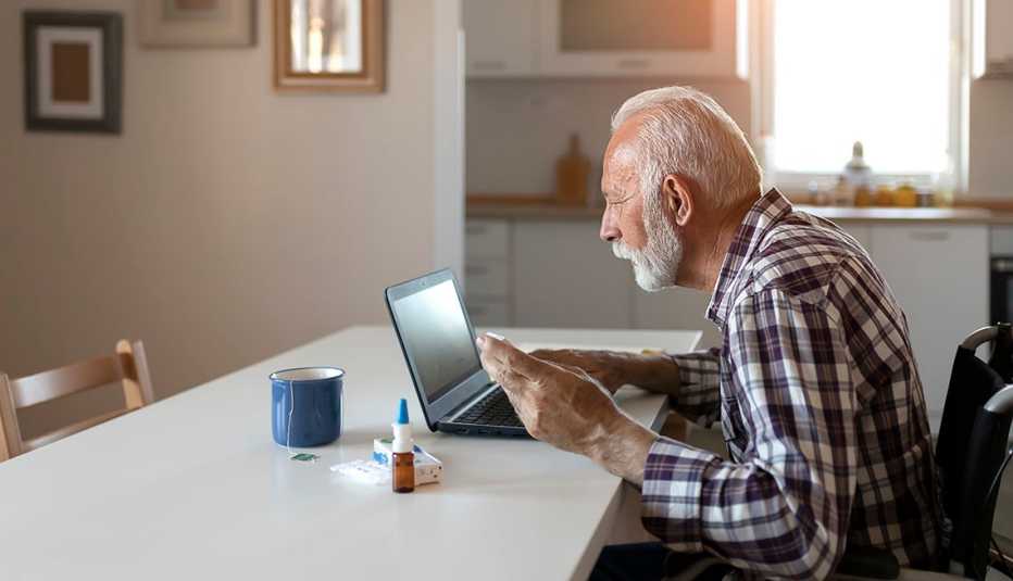man in a wheelchair sits at a table and uses a computer