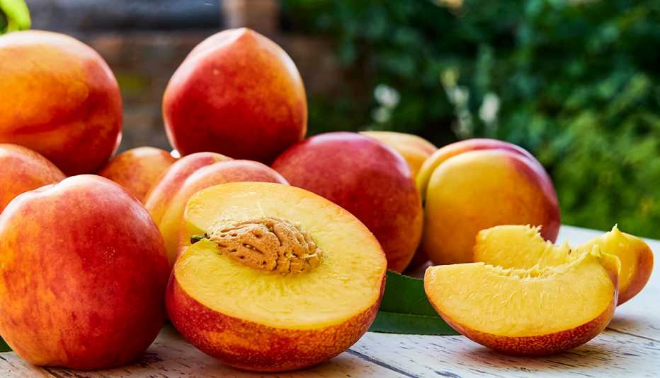 Whole and cut peaches on an outdoor table.