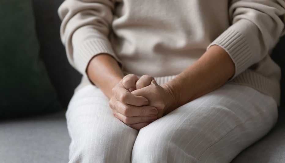 Woman with her hands on her lap and sitting on a couch