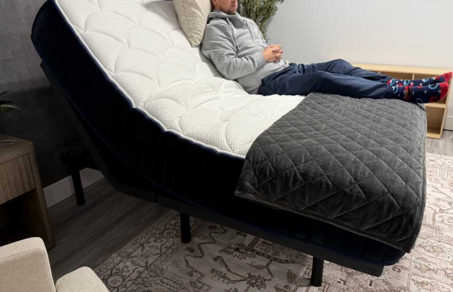 A man sitting on the DreamCloud Premier Adjustable Base and mattress in the upright position.