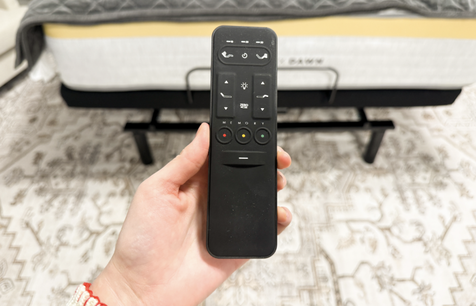 The remote of the Helix Adjustable Base held up in front of the bed
