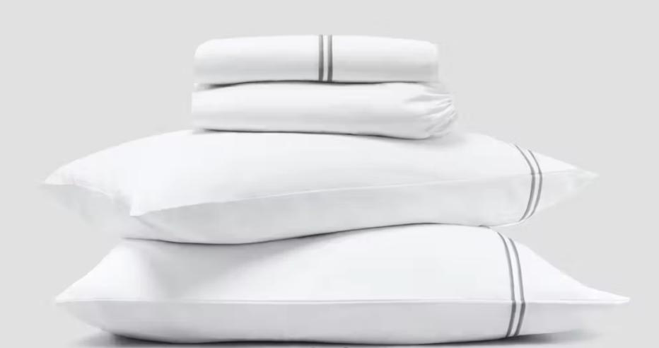 The Saatva Organic Sateen Sheet Set in a stack with pillows

