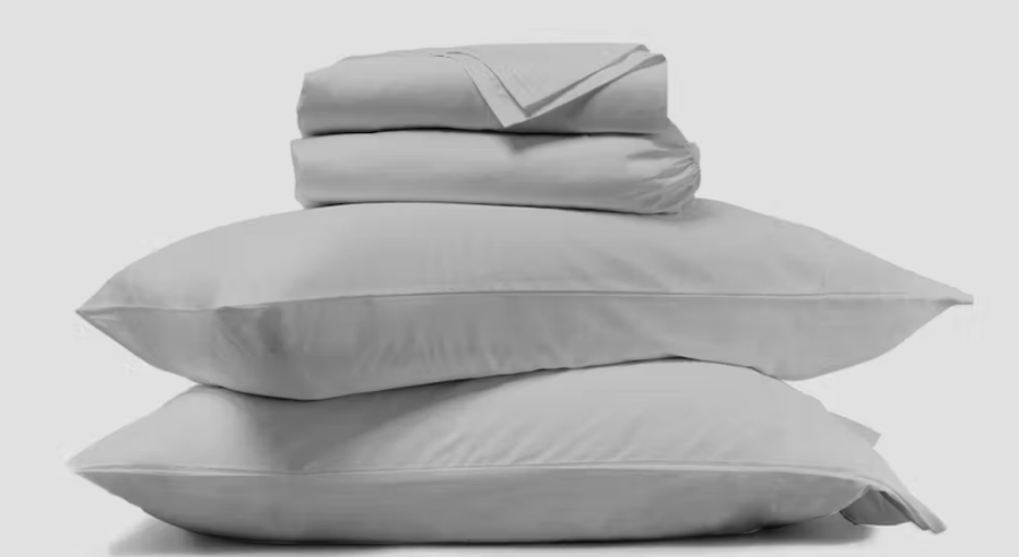The Saatva Organic Sateen Sheet Set in a stack with pillows