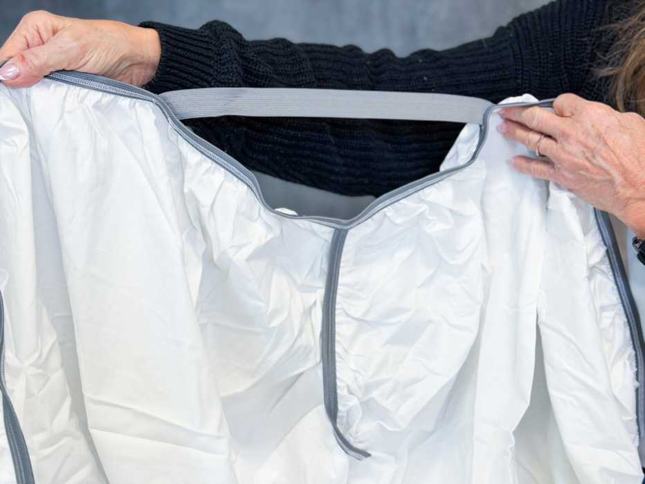 A woman holding up the corner of the Sleep Number True Temp fitted sheet.