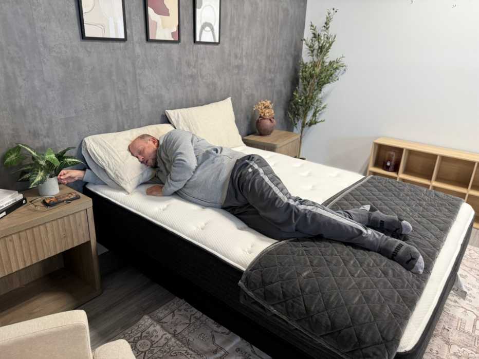 Man lies on his side with his eyes closed on a mattress