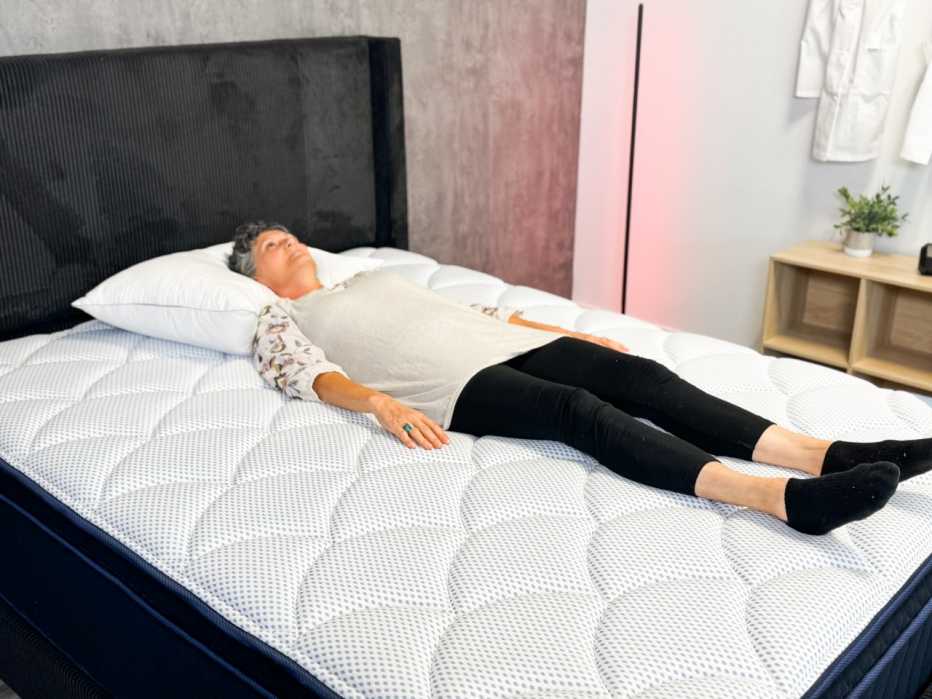 Woman lies on her back on a mattress and stares straight up at the ceiling