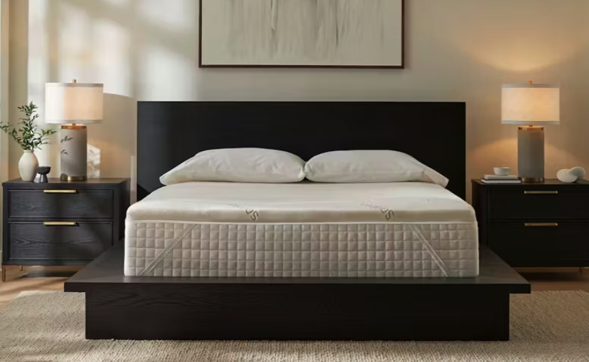 The Saatva Natural Latex Topper on a bed on display