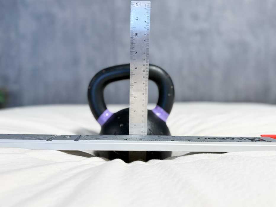 The sinkage of a 45-pound kettlebell on the Birch Plush Organic Topper being measured by a lab tester