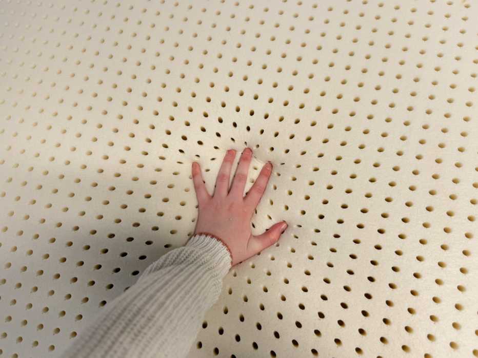A hand pressing into the PlushBeds Organic Latex Mattress Topper