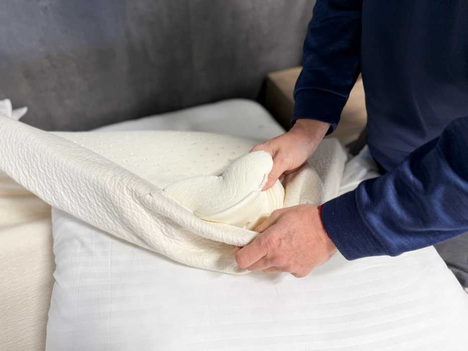 A man opening the cover of the Avocado Eco Organic Latex Topper