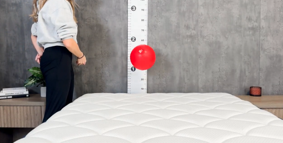 A woman dropping a 15-pound ball on the DreamCloud Classic Hybrid to test how high it bounces.