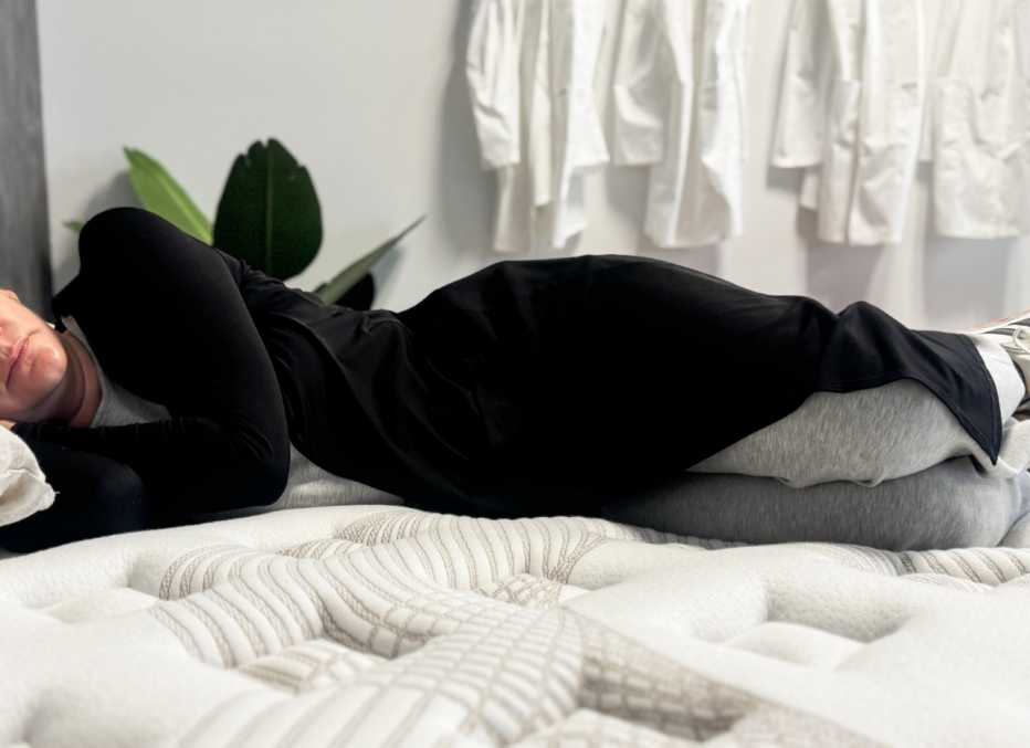 A woman lies on her side on a plush, comfortable bed