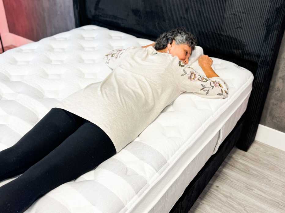 A woman lies on her stomach on a white bed