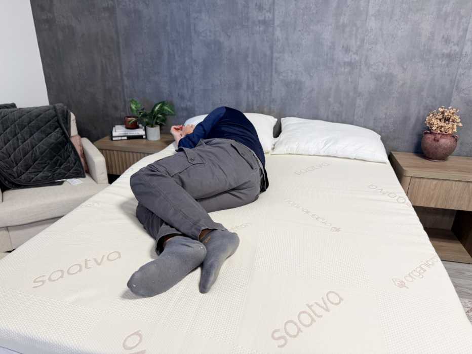 A man lying on his side on the Saatva Graphite Memory Foam Mattress Topper