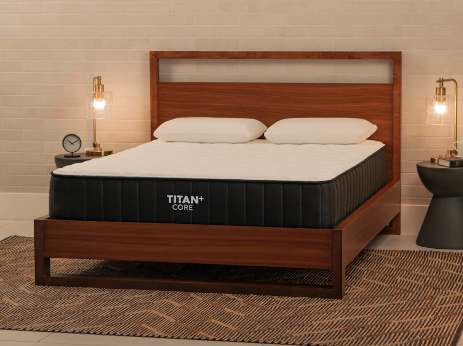 The Titan Plus Core mattress in a dim bedroom with lamps.