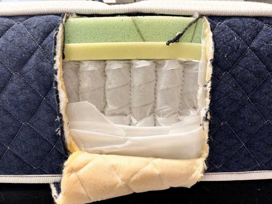 Side of mattress is cut open revealing the foam inside