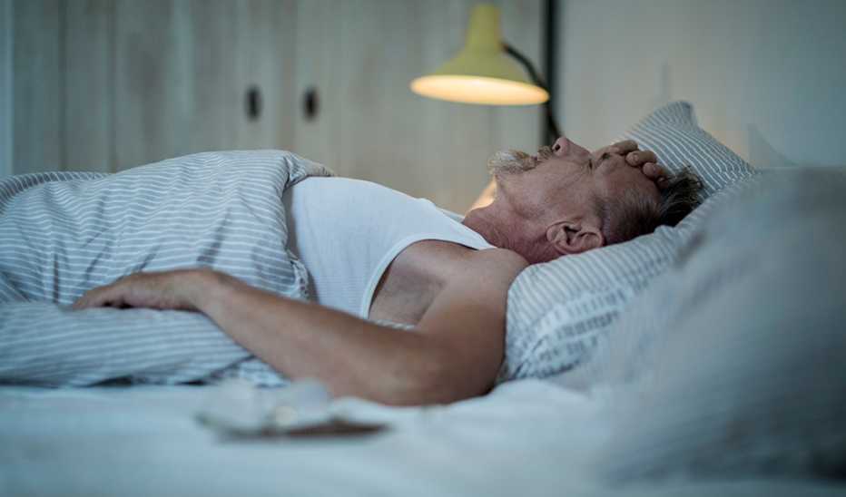 A man appearing stressed as he sleeps in bed