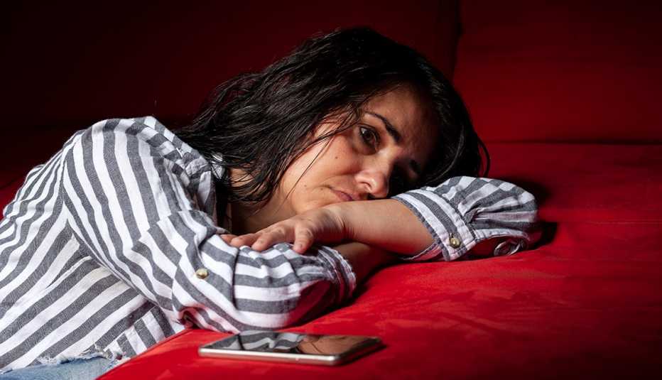 close up of a sad woman with sleep deprivation resting her head on her arms while lying on her bed