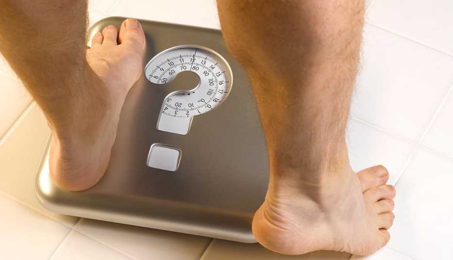 Man's feet stepping on scale that has a question mark on it