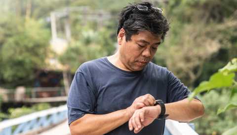 close up of a man tracking his step count on his smartwatch while walking on a paved trail in the woods man checking the pedometer on his smartwatch to track the number of steps per day he has taken