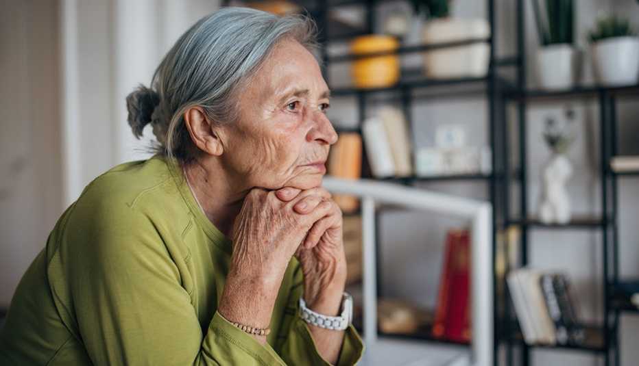 a lonely woman in a green shirt resting her chin on her hands in her bedroom