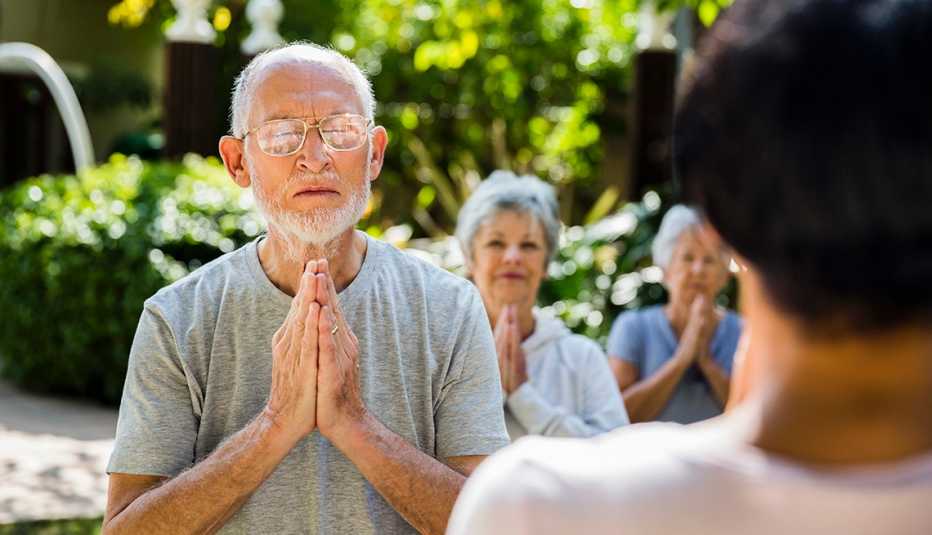 a group of older people meditating outdoors on a sunny day