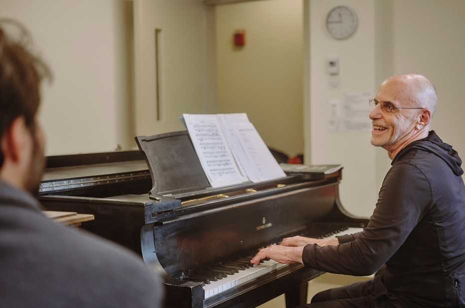 Jeffrey Galvin smiles while playing the piano as his teacher Jason Solounias looks on jeffrey galvin smiling while playing the piano