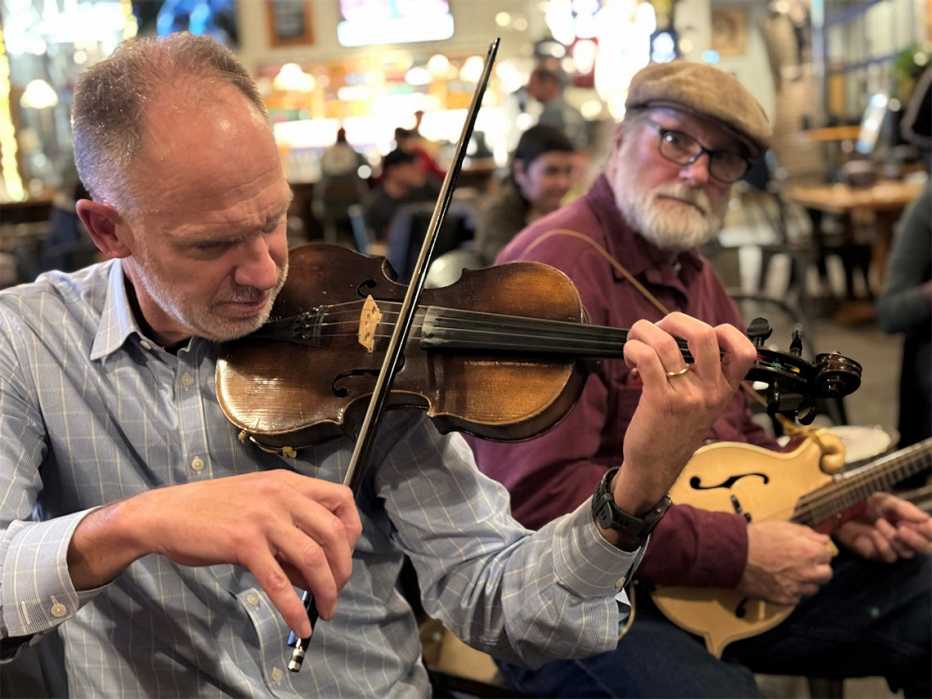 jonathan burdette playing the fiddle sitting next to another man with a mandolin