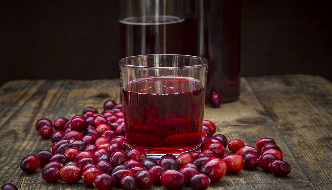 a glass of cranberry juice on a table surrounded by cranberries