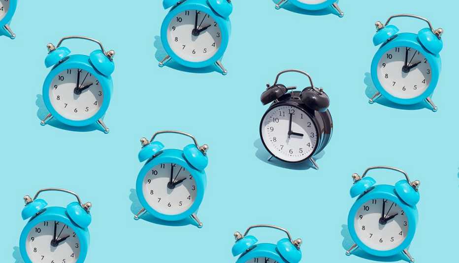 pattern of blue retro alarm clocks show 2 o'clock and one black shows 3 o’clock. Changing to daylight savings time