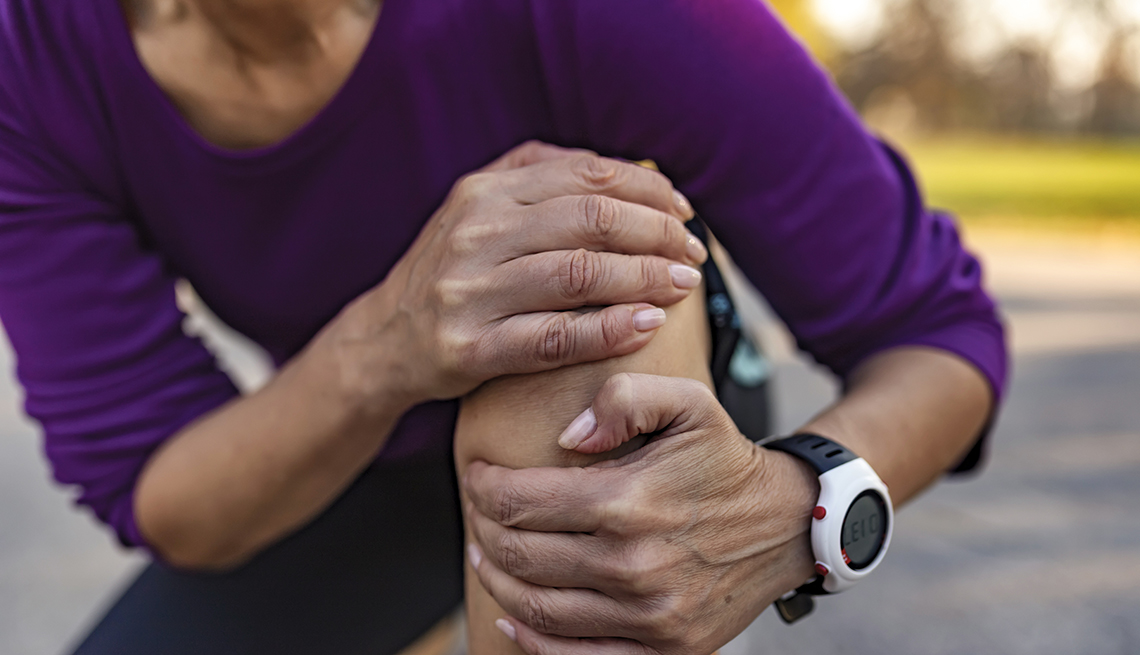 woman holding her injured leg and knee after a run outside