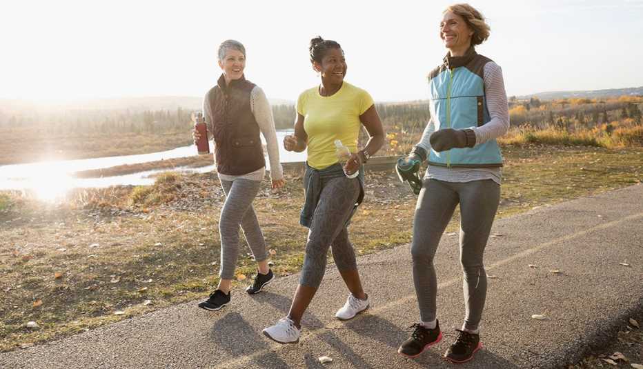 Women power walking exercising on sunny path in autumn park