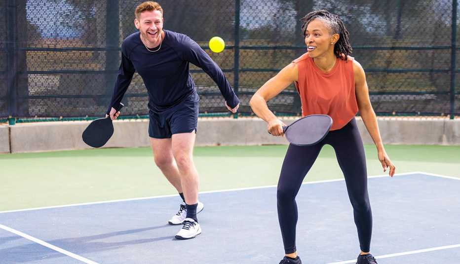 a man and a woman are smiling while playing pickleball