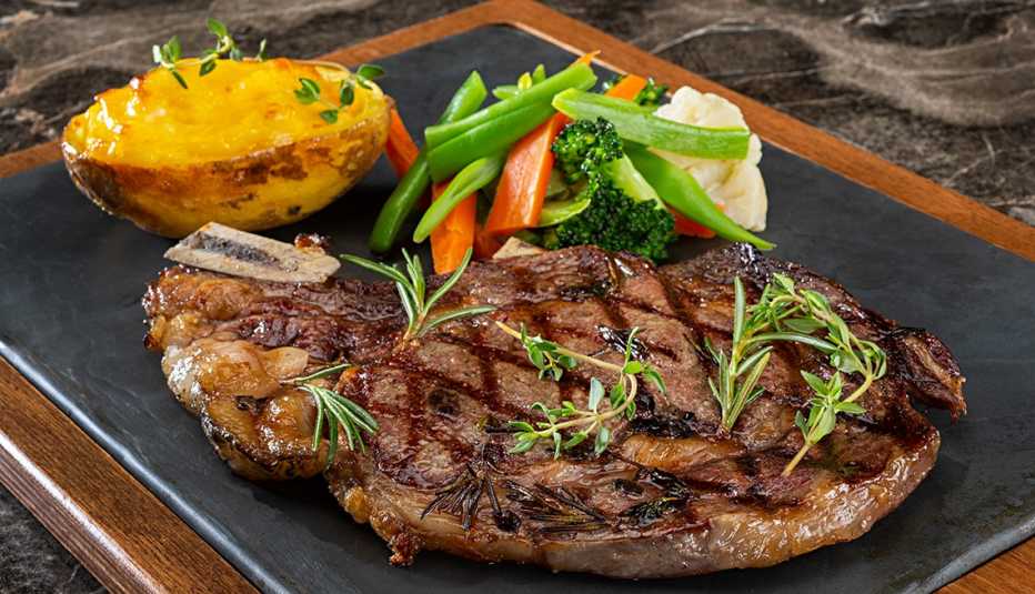 Close up of steak, vegetables and a baked potato on a platter. Close up of steak, vegetables and a baked potato on a platter.