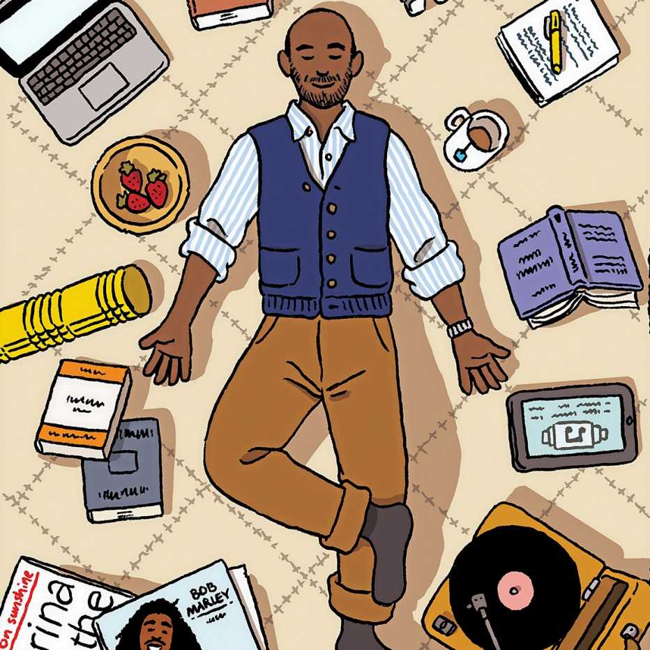 smiling man laying on floor listening to record player surrounded by book, tea, records, a dish or strawberries